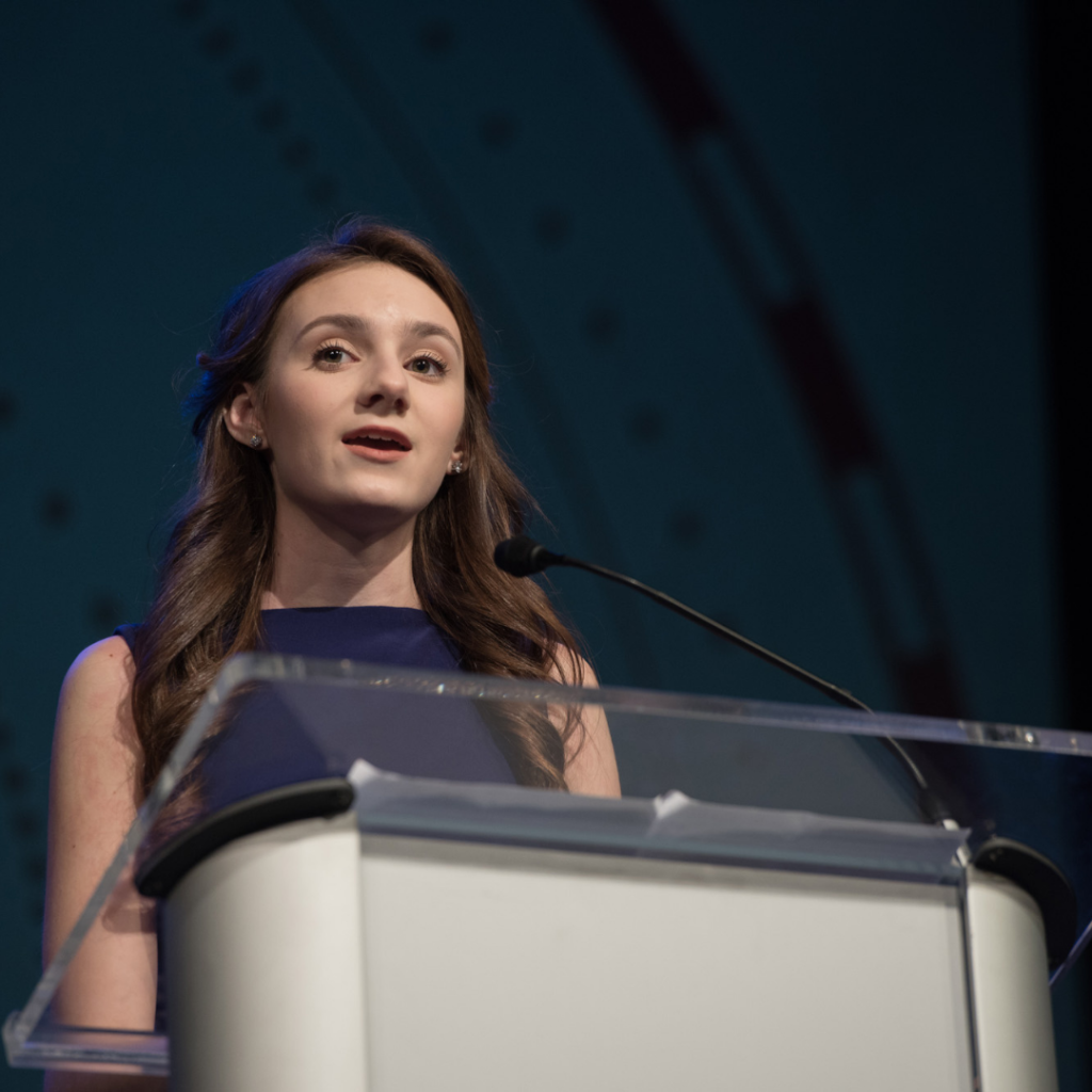 A female Dayspring Christian Academy student speaking at a podium